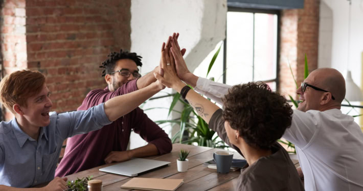 Erfolgreiches Team an einem Tisch - Themen: Sozialbeziehungen und Unternehmenskultur fördern dank INQA-Coaching